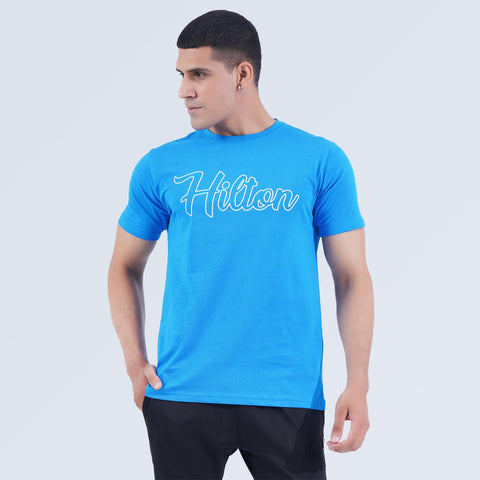 Angled front view of Sky Blue Crest Tee, soft 100% cotton crew neck T-shirt by Hilton Aesthetics