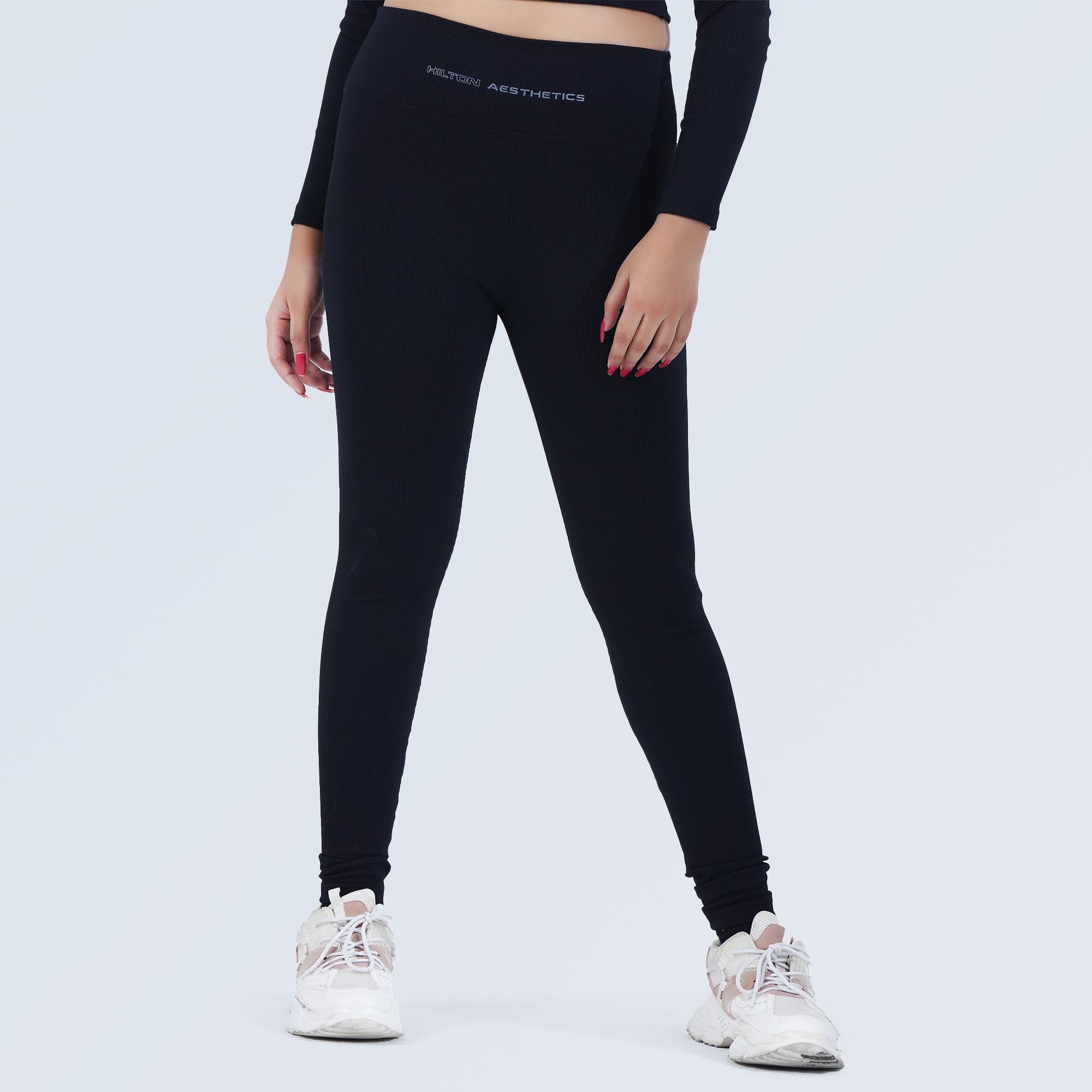 Woman wearing black Hilton Aesthetics high-waist ribbed leggings, front view