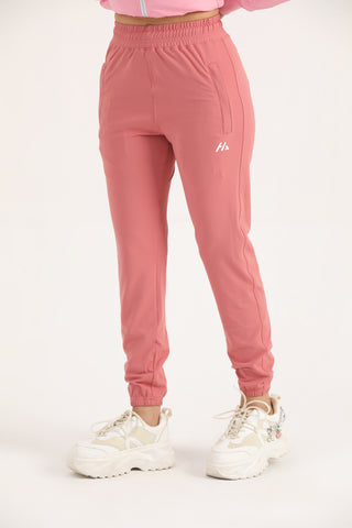 Woman wearing light coral Hilton Aesthetics Trace Joggers, angled front view