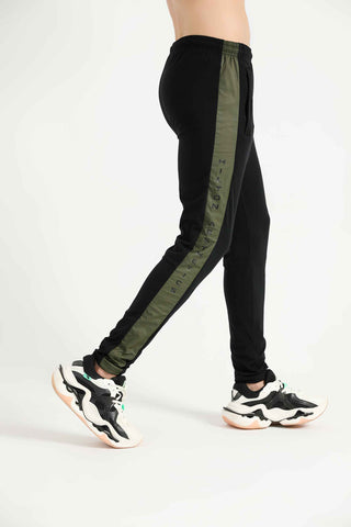 Model wearing black Hilton Aesthetics Elite Joggers with contrast side panels, side view