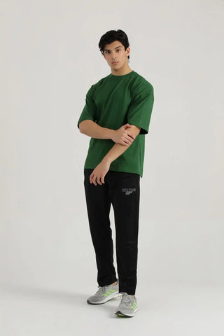 Full body view of a model wearing black Lifting Relaxed Joggers and a green t-shirt by Hilton Aesthetics.