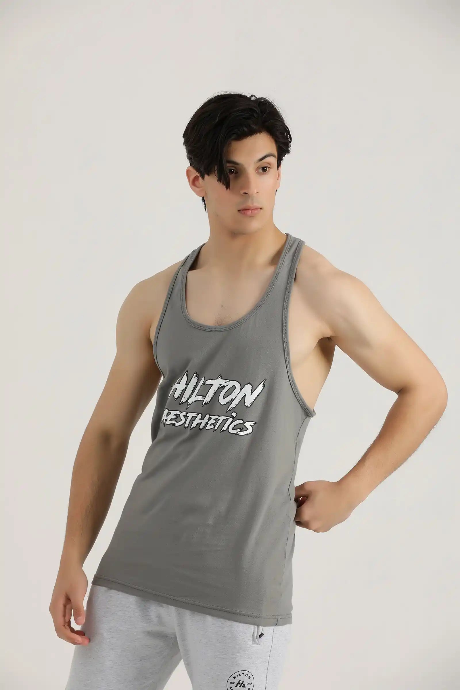 Man wearing a grey Hilton Aesthetics Power Stringer Tank Top, front view