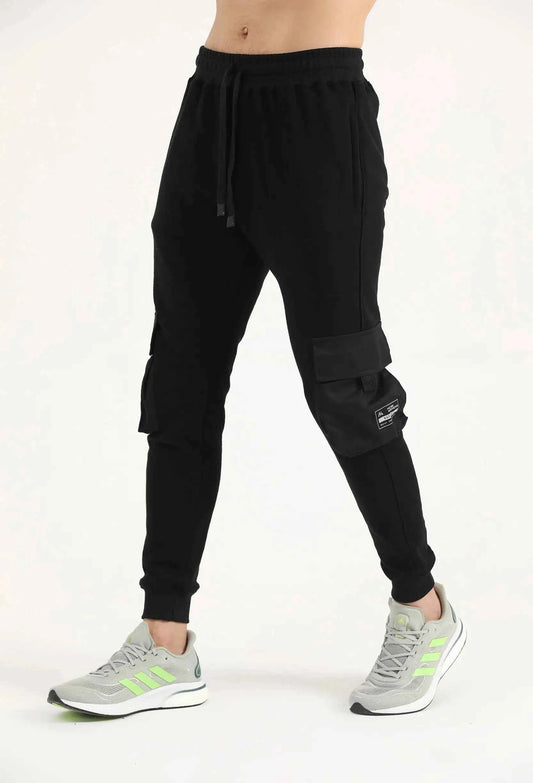 Man wearing black Hilton Aesthetics Crest Cargo Joggers with side pockets, angled front view