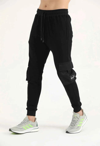 Man wearing black Hilton Aesthetics Crest Cargo Joggers with side pockets, angled front view