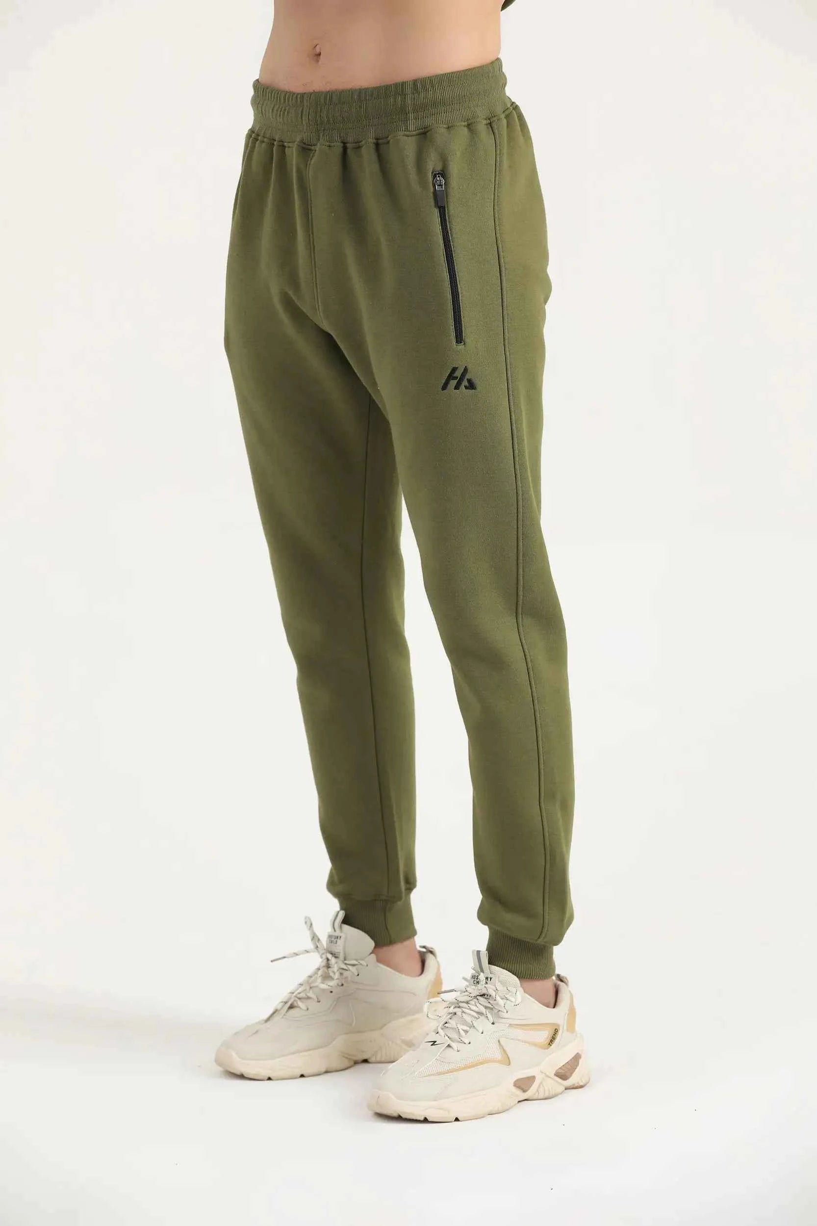 Man wearing dark olive green Hilton Aesthetics Flexx Joggers, side view